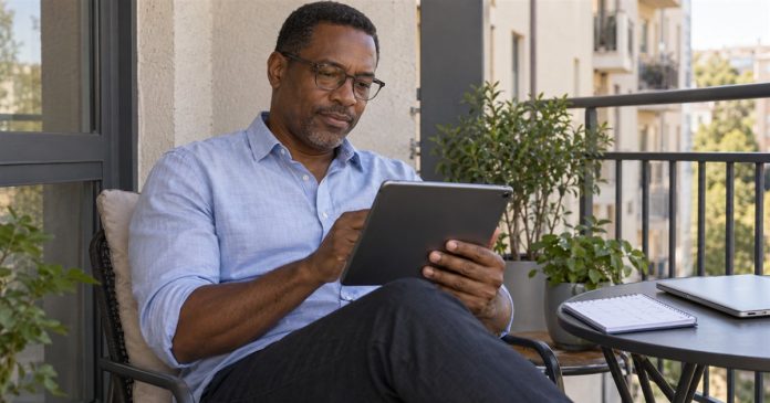 Email Psychic Readings for a Busy Schedule: Plan the Request and Review Man reviewing an email on a tablet during a quiet break on his home balcony.