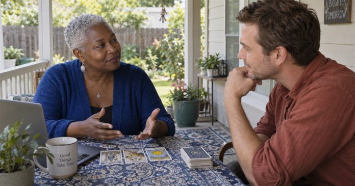 Reader and client discussing printed tarot cards beside an open laptop on a modest back porch.