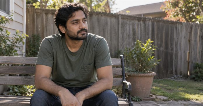 Man taking a quiet reflective break on a bench in an ordinary backyard.