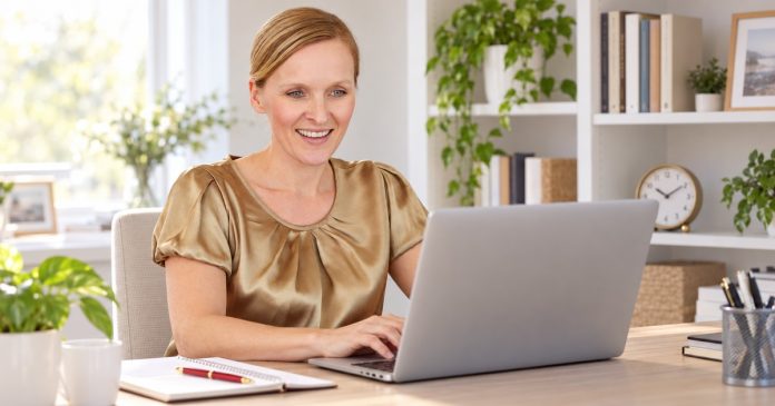 Woman patiently reading email on her laptop in a bright office